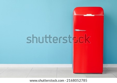 Stylish retro fridge near blue wall in room