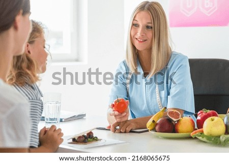 Young beautiful dietitian is standing in the office holding an apple Royalty-Free Stock Photo #2168065675