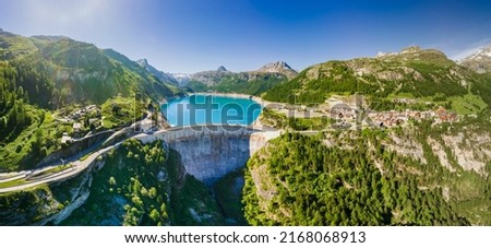 Water dam and reservoir lake aerial panoramic view in French Alps mountains generating hydroelectricity. Low CO2 footprint, decarbonize, renewable energy, sustainable development. Hydro power. Royalty-Free Stock Photo #2168068913