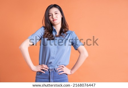 Young Asian business woman posing on orange background