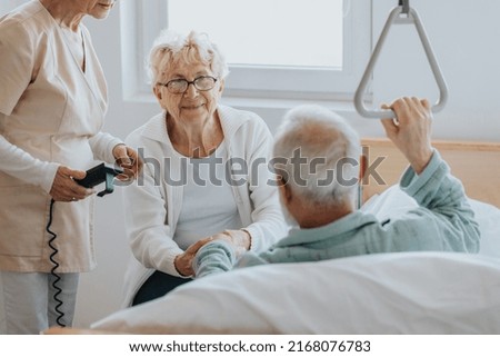 Senior patient gets up from the hospital bed by helping himself with a special handle Royalty-Free Stock Photo #2168076783