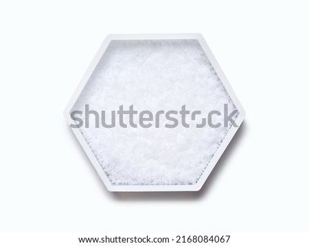 Sodium Hydroxide Pellets in hexagonal molecular shaped container on white background. Top View Royalty-Free Stock Photo #2168084067