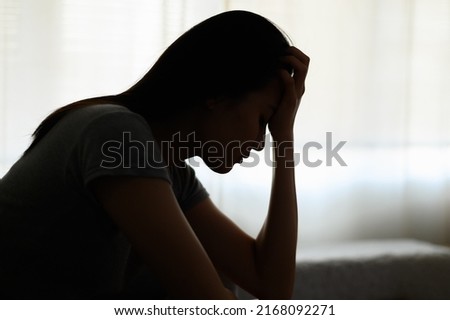 Silhouette photo of young Asian woman feeling upset, sad, unhappy or disappoint crying lonely in her room. Young people mental health care problem lifestyle concept. Royalty-Free Stock Photo #2168092271