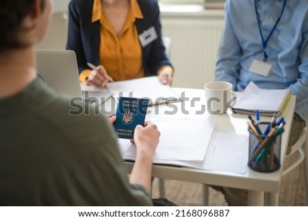 Woman and man volunteers helping Ukrainian woman to fill in forms at asylum centre. Royalty-Free Stock Photo #2168096887