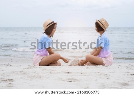 Two Young Girl Playing with Sand at Beach.