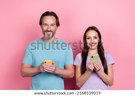 Photo of two peaceful cheerful people hold use telephone toothy smile isolated on pink color background