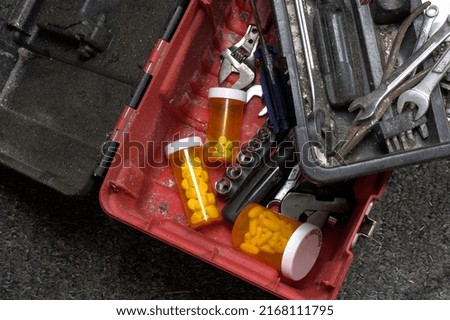 Prescription medication bottles hidden at the bottom of a tool box. Royalty-Free Stock Photo #2168111795