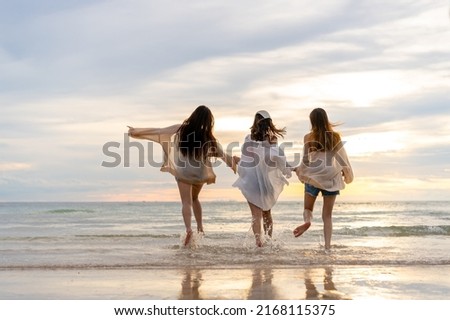  Group of Young Asian woman in walking and playing together on tropical beach at summer sunset. Happy female friends enjoy and fun outdoor activity lifestyle on holiday travel vacation at the sea