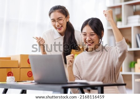 Two Young Asian women are happy and excited after a new order from SME customer, commercial checking, online marketing, Entrepreneur packing boxes, SME sellers, and freelance online sales concept,  Royalty-Free Stock Photo #2168116459