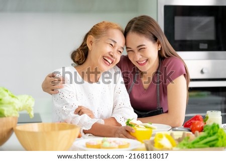 mother and daughter cooking in the kitchen, mother and daughter hugging to love on mother's day, Asian family