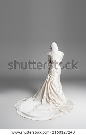 back view of muslim bride in gorgeous wedding dress standing on grey Royalty-Free Stock Photo #2168127243