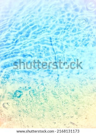 Defocus blurred transparent blue colored clear calm water surface texture with splashes and bubbles. Trendy abstract nature background. Water waves in sunlight. Blue water background.