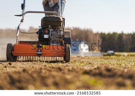 Closeup shoot of man using aerator machine to scarification and aeration of lawn or meadow Royalty-Free Stock Photo #2168132585