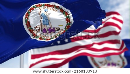 The Virginia state flag waving along with the national flag of the United States of America. Virginia is a state in the Mid-Atlantic and Southeastern regions of the United States Royalty-Free Stock Photo #2168133913