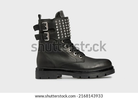 Black women's fashion Combat boot, spring autumn shoe isolated on white background. Female leather luxury casual footwear with buckle, rivet, spikes, rough sole. Single Royalty-Free Stock Photo #2168143933