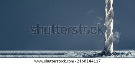 Horizontal shot of metal drill bit make holes in aluminum billet on industrial drilling machine with shavings. Smoke rises from the drill. The force of friction. Royalty-Free Stock Photo #2168144117