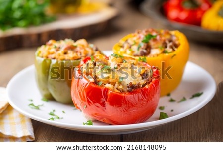 Stuffed peppers, halves of peppers stuffed with rice, dried tomatoes, herbs and cheese in a baking dish on a blue wooden table, top view. (Turkish name; biber dolmasi) Royalty-Free Stock Photo #2168148095