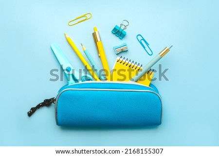 Top view of pencil case with school supplies on blue background. Back to school concept Royalty-Free Stock Photo #2168155307