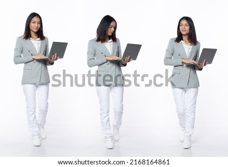 Full length 20s young Asian Woman teacher student business, walking forward left right, wear formal blazer pants shoes. Smile Office female carry notebook laptop over white background isolated