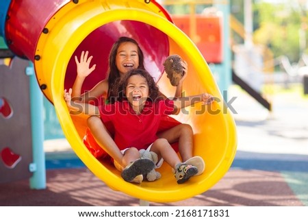 Kids on playground. Children play outdoor on school yard slide. Healthy activity. Summer vacation fun. Child playing in sunny park. Kid having fun on colorful slide. Royalty-Free Stock Photo #2168171831