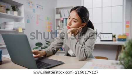 Young Asian businesswoman sit on desk with laptop overworked tired burnout syndrome at office. Exhausted lady with sleeply eye at workplace, Girl not enjoy unhappy with work, Work mental health.