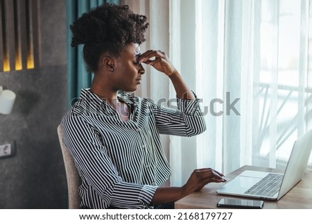 Young frustrated woman working at desk in front of laptop suffering from chronic daily headaches, treatment online, appointing to a medical consultation, electromagnetic radiation, sick pay