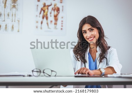Portrait of female doctor seating in her office at clinic. Friendly Latin American female doctor at the hospital looking at the camera and smiling. Confident female doctor at office desk Royalty-Free Stock Photo #2168179803