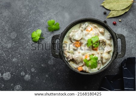 Spicy stewed chicken gizzard, giblets, offal in cast iron pot. Top view, copy space. Royalty-Free Stock Photo #2168180425