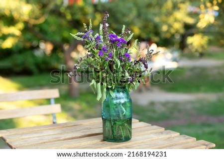 Bouquet of summer flowers in ceramic vase on table on terrace. Fresh Field flowers in vase. Cozy home decor of patio yard. Still life. Women day or wedding concept. festive background, copy space