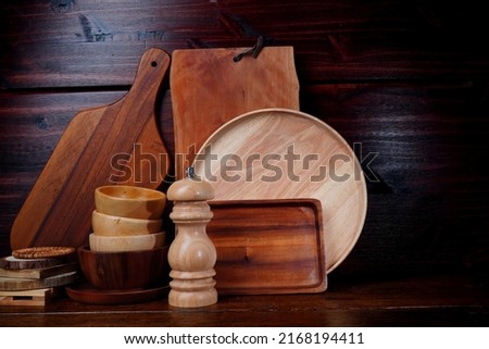 Wooden chopping boards, cups, trays, and kitchen utensils on a wooden table.