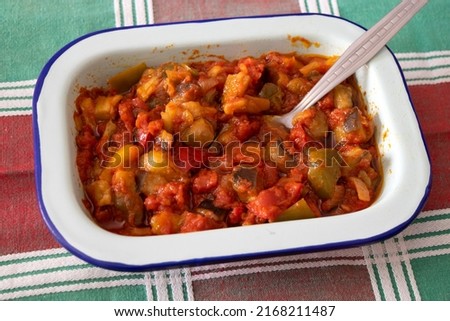 Vegetable mix with tomato called "samfaina" in a metal porcelain tray on a classic green and red checkered tablecloth with a spoon ready to serve Royalty-Free Stock Photo #2168211487