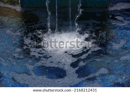 Fountain waterfall with clear splashing bubbling water over blue tiles