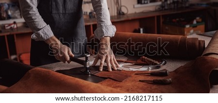 Tailor processing hammers seam on leather goods, banner Handmade craftsman. Royalty-Free Stock Photo #2168217115