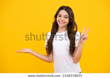 Impressed teenage girl showing recommendation copyspace. Child teenager points away, pointing aside at copy space. Happy teenager, positive and smiling emotions of teen girl.
