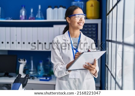 Young african american woman scientist write on report document at laboratory Royalty-Free Stock Photo #2168221047