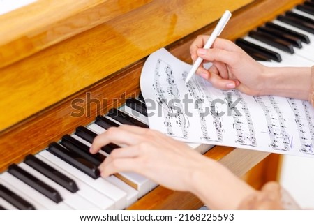 Woman's hands playing piano at home. The woman is professional pianist arranging music using piano keyboards. Musician practicing keyboard composing music. Artist create instrumental acoustic melody. Royalty-Free Stock Photo #2168225593