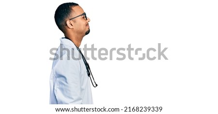 Young african american man wearing doctor uniform and stethoscope looking to side, relax profile pose with natural face and confident smile. 
