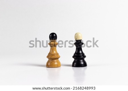 Creative black and white wooden pawn chess figures against white background with shadows and reflections. Side view. Board game concept. Royalty-Free Stock Photo #2168248993