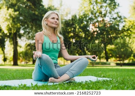 Close up portrait of caucasian mature woman in sporty outfit relaxing meditating feeling zen-like on fitness mat in public park outdoors. Healthy active lifestyle Royalty-Free Stock Photo #2168252723