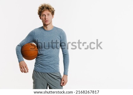 Young ginger man wearing sportswear posing with basketball isolated over white background