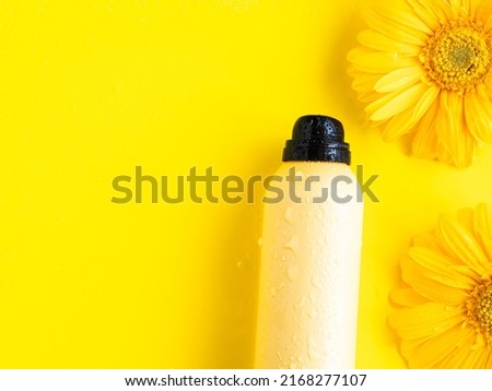 Yellow sunscreen spray and daisy flowers, copy space. Sun protection concept monochrome background