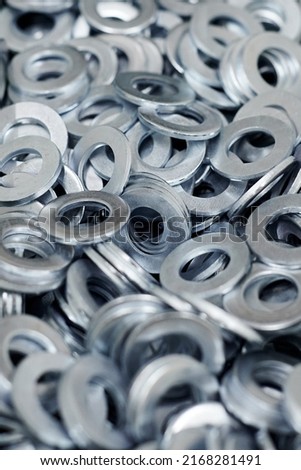 Bunch of stainless steel galvanized flat washers for fastener screws, nuts or bolts, hardware background. Stack of flat washers for distribute load of threaded fastener, close up Royalty-Free Stock Photo #2168281491