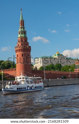 a white pleasure boat with tourists  floats on the Moscow River past the walls of the Moscow Kremlin