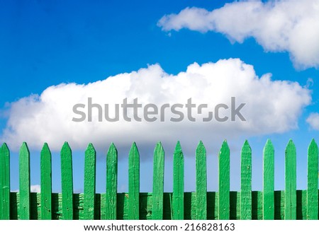 green wooden fence on a blue sky background