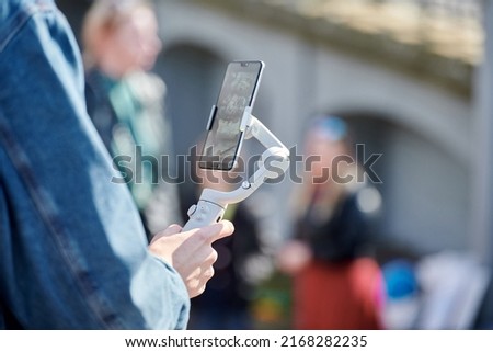 Blogger filming outdoor event on smartphone with gimbal stabilizer, video blogging for new followers. Video shooting content for social media networks, vlog video making Royalty-Free Stock Photo #2168282235