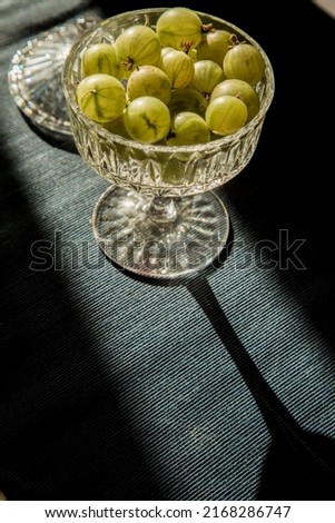 Juicy green gooseberries are lying on the table, served berries, berry snack or breakfast, vintage retro plate with gooseberries in the sun, summer local berries