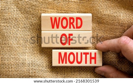 Word of mouth symbol. Concept words Word of mouth on wooden blocks on a beautiful canvas table canvas background. Businessman hand. Business, finacial and word of mouth concept. Copy space.