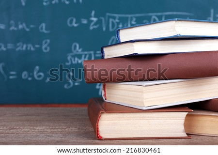 Books on wooden table on blackboard background