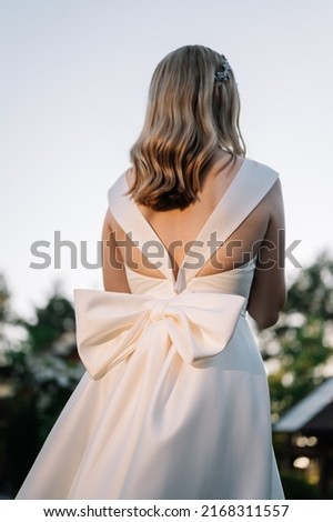 Young woman, blonde bride in a wedding vintage dress with a big bow shot from behind Royalty-Free Stock Photo #2168311557