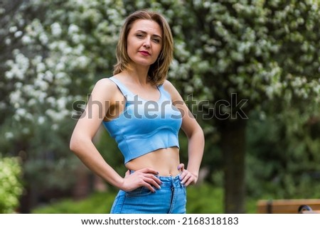 Portrait of a young happy woman of thirty plus years old on a blurred background of flowering trees. Copyspace for text